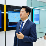 A professional Vietnamese government official, fully clothed in a modest, modern business suit, stands in a brightly lit, contemporary digital government service center. In the background, citizens are calmly interacting with user-friendly digital kiosks and large screens display transparent public service data. The scene emphasizes efficiency and technological advancement in public administration. Perfect anatomy, correct proportions, natural pose, well-formed hands, proper finger count, natural body proportions, professional photography, high quality, safe for work, appropriate content, fully clothed, professional.